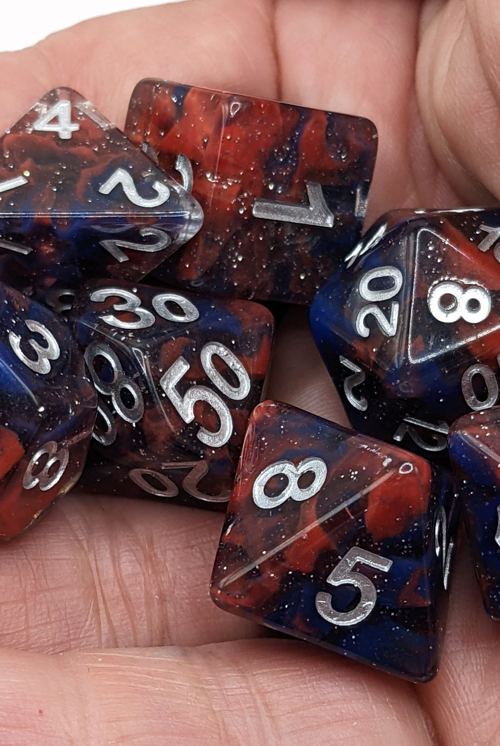 Celestial Dice Red and Blue held in the hand and ready to roll